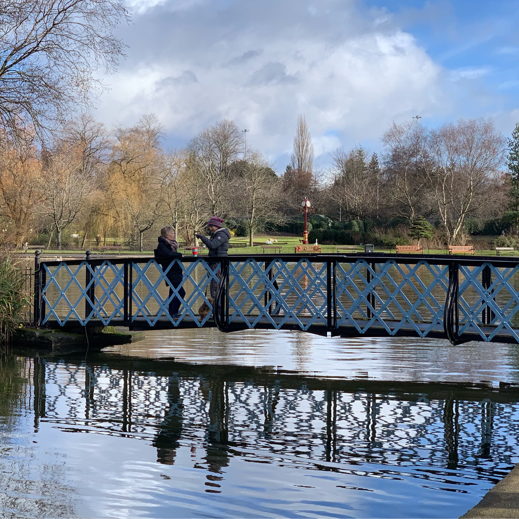 two people on bridge over pond