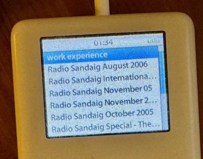 ipod classic screen with Radio Sandaig podcast episodes listed.