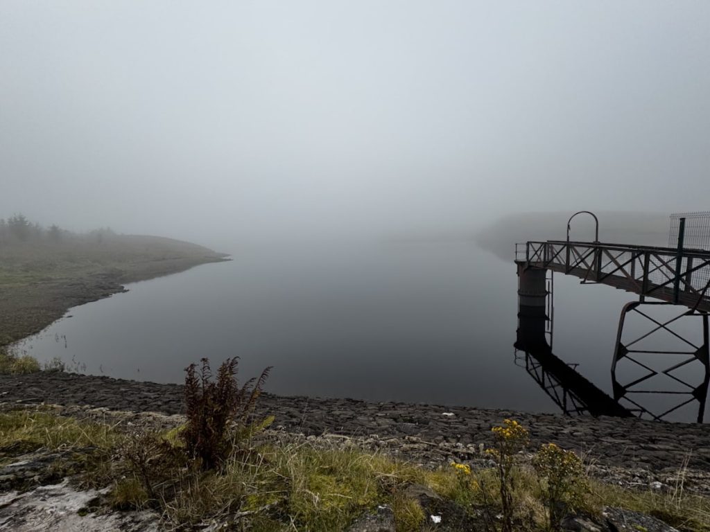 Misty scene at Jaw Reservoir with a pier over calm water and a foggy shoreline.
